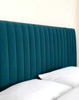 Elegant emerald green upholstered headboard with vertical channel tufting, complementing white bedding on a presumably matching bed.