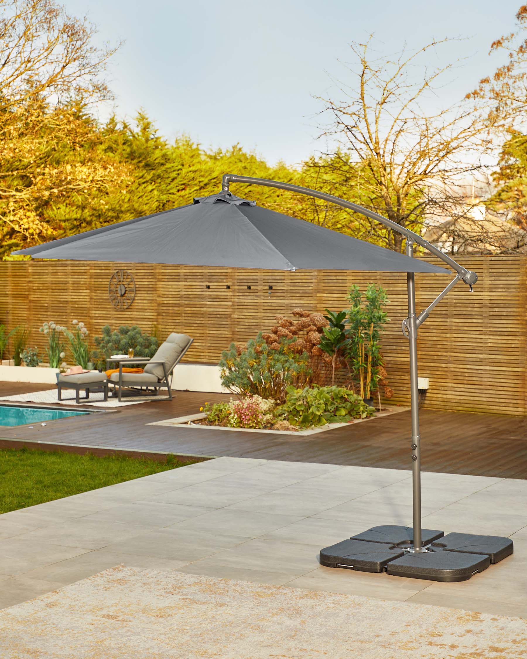 A sleek gray cantilever umbrella stands beside a lounge chair and pool, perfect for outdoor relaxation and shade.