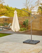 A stylish outdoor umbrella stand with a large beige canopy, set on a sturdy black base, complements the tranquil garden space.