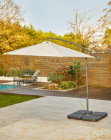 A stylish outdoor umbrella with a sleek metal base, paired with a modern lounge chair on a patio near a pool.