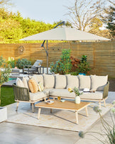 Stylish outdoor sectional sofa with plush cushions, a wooden coffee table, and a large umbrella for shade.