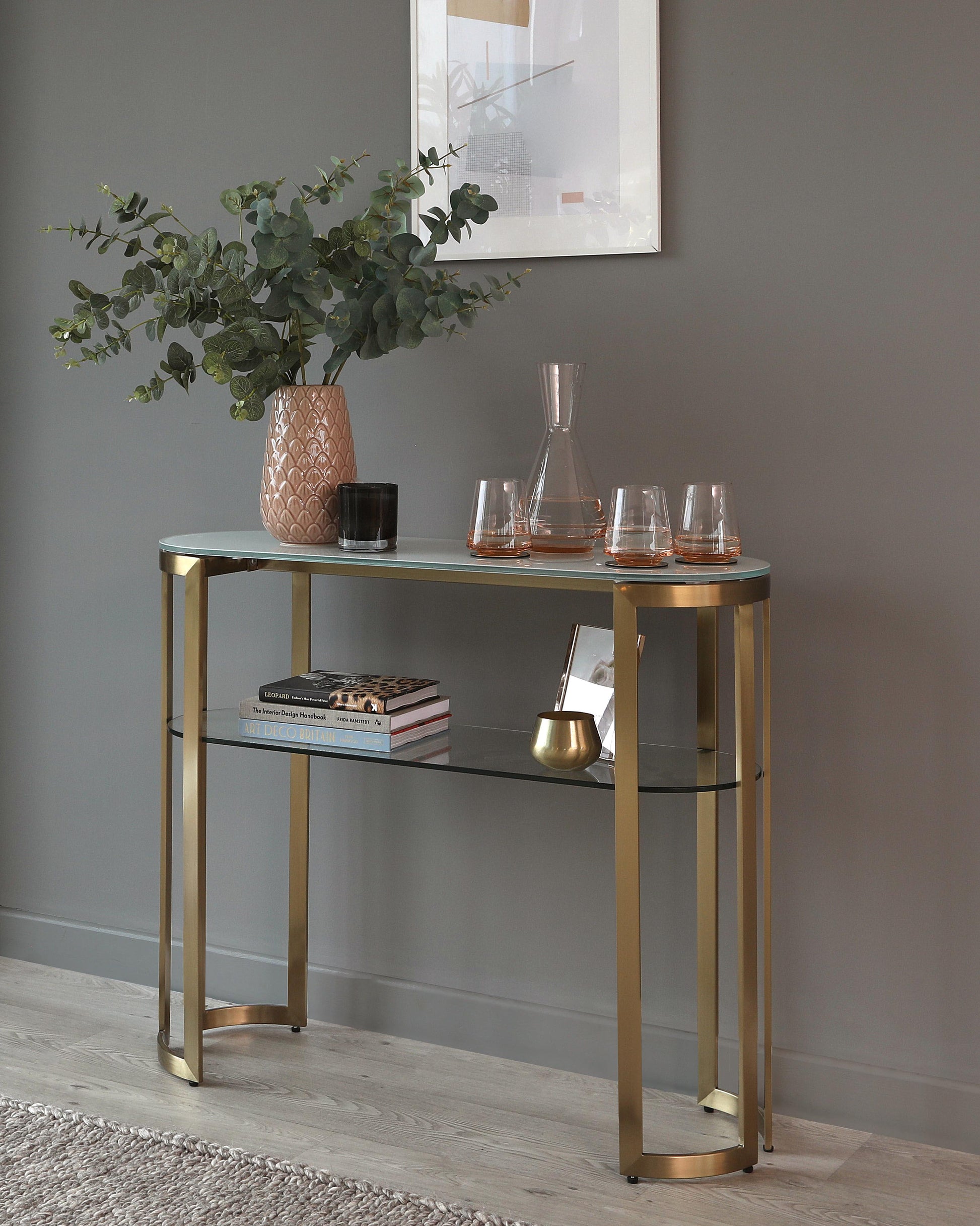 Elegant metal console table with a glass top and a lower glass shelf, finished in a brushed gold tone.