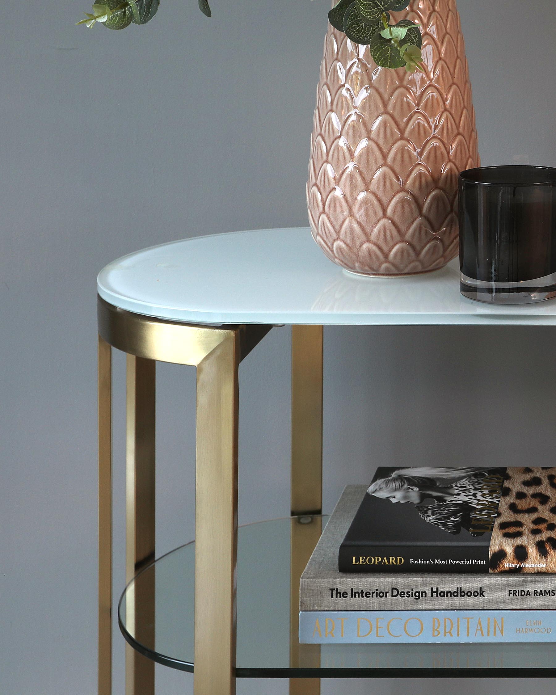 Round white-top side table with gold metal legs and a second-tier glass shelf.