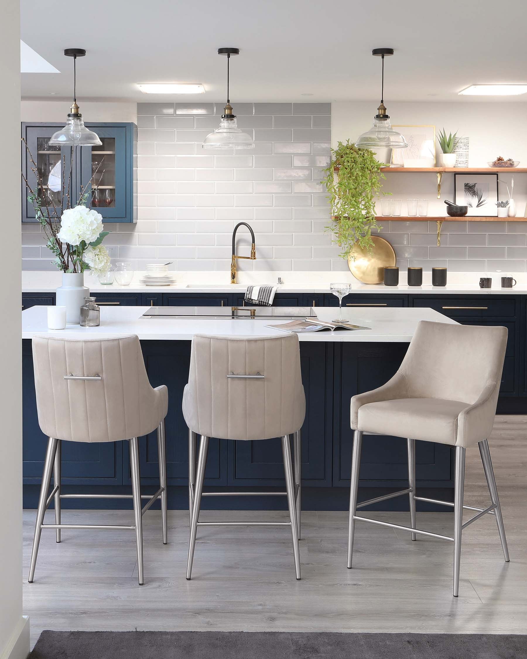 Modern kitchen with elegant furniture including two plush, light beige bar stools with backrests and sleek, metallic legs, and one coordinating armchair with a comfortable backrest and arm support, all complementing a stylish kitchen island.