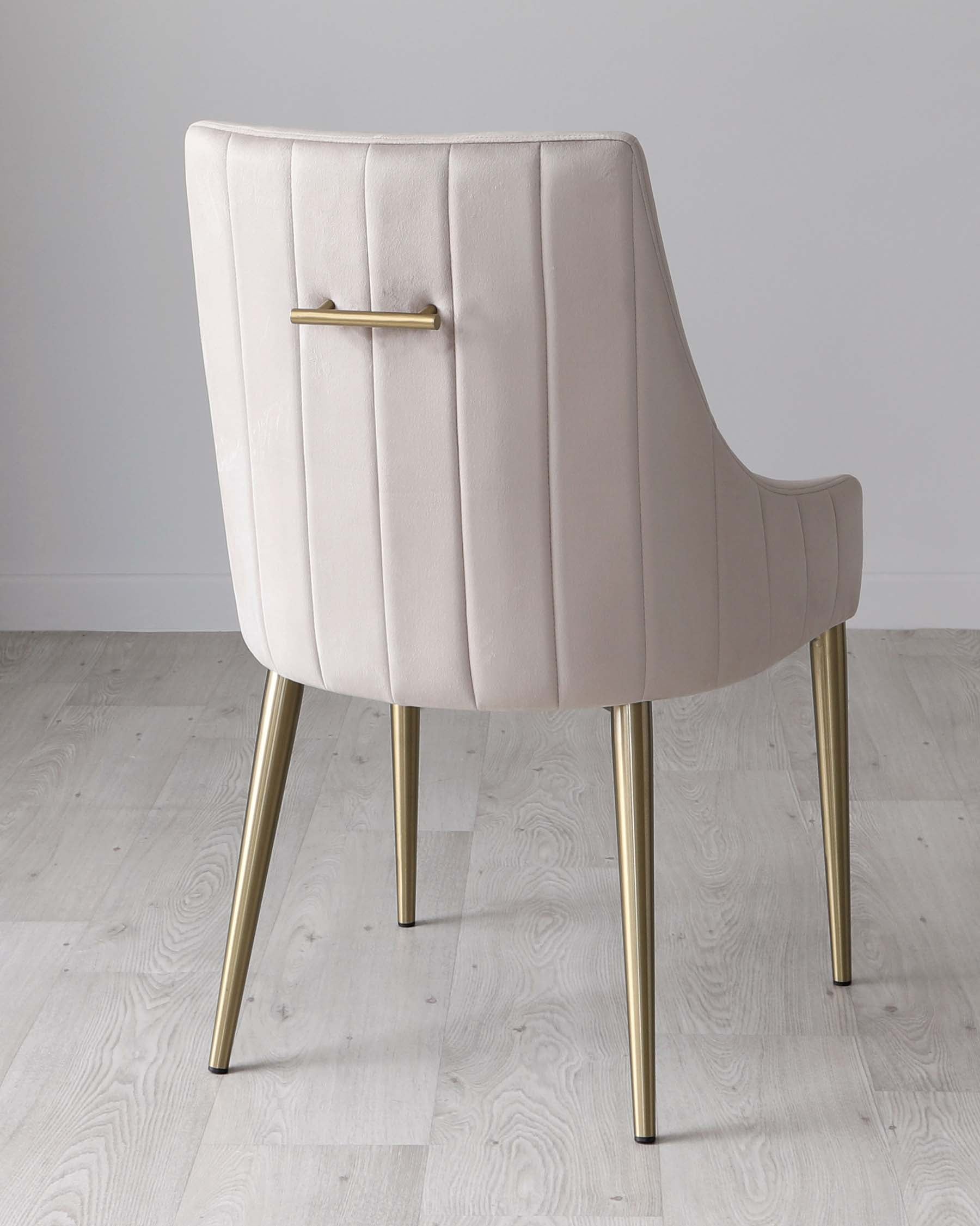 Elegant modern dining chair with a blush pink velvet upholstery and channel tufting on the rounded back. Featuring sleek brass-finished metal legs that taper to a subtle point.