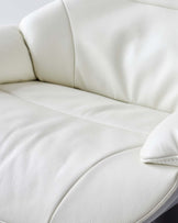 Close-up view of a contemporary cream-colored leather sofa with plush cushioning and a textured surface.