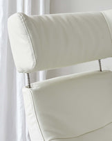 Close-up of a modern white leather chair with detailed stitching and metal accents.