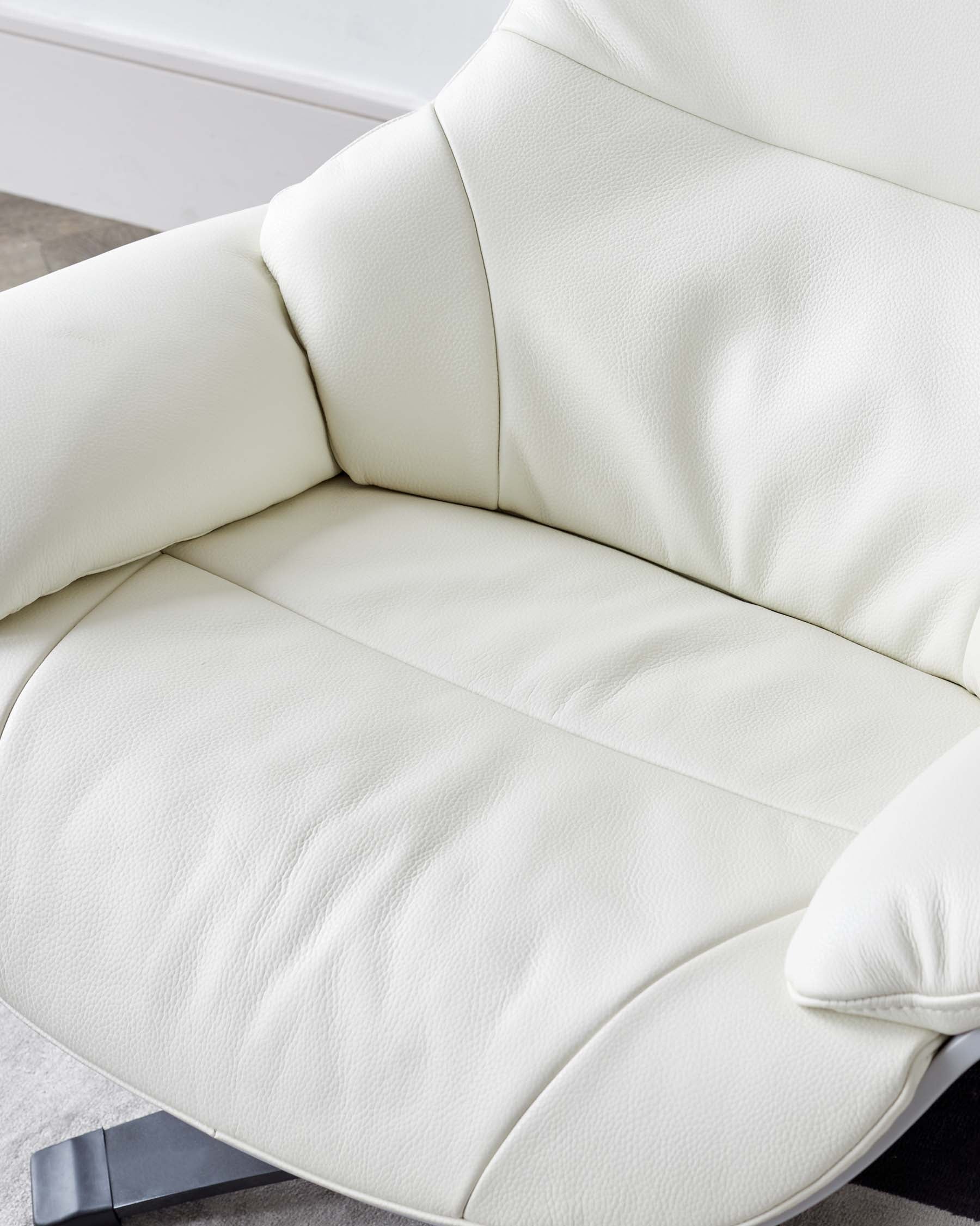 Modern cream-colored leather armchair with a curved backrest and a plush, segmented seat cushion, showcasing a sleek and contemporary design.