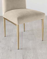 Modern minimalist chair with a plush, taupe velvet seat and a backrest atop four sleek, tapered brass legs.