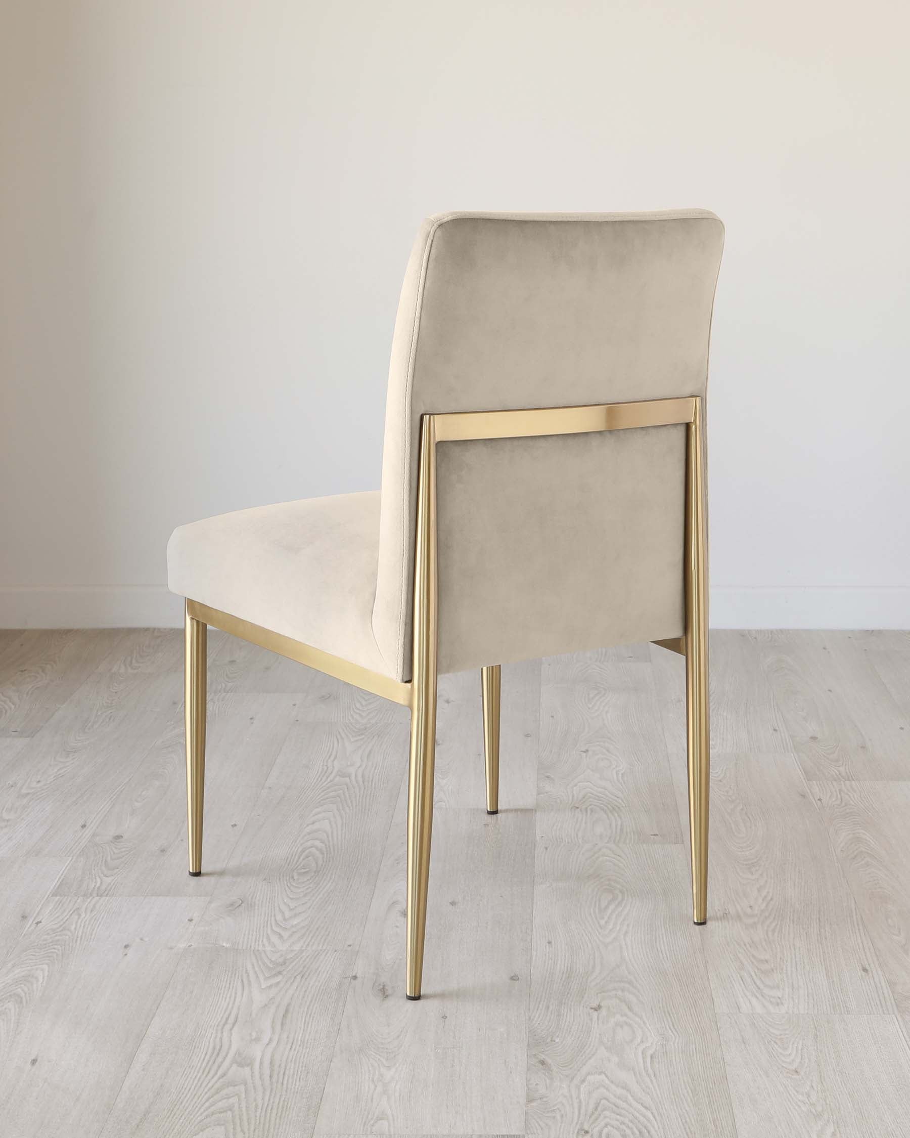 Elegant modern chair with a beige velvet upholstery and sleek brass legs, featuring a high back and a comfortable, cushioned seat, set against a neutral background with light wooden flooring.