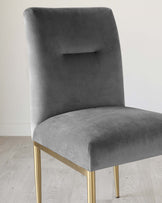 Elegant modern dining chair with a sleek, grey velvet upholstery and a minimalist rectangular cut-out in the high backrest. The chair features four slender, tapered metal legs with a brushed gold finish, providing a luxurious contrast to the soft fabric. The simple yet sophisticated design is set against a neutral background, highlighting the chair's contemporary aesthetic.