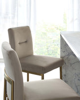 Elegant modern dining chairs with beige upholstery and a sleek marble dining table with white and grey veining, highlighted by a backdrop of sheer curtains and natural light.