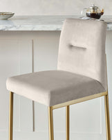 Elegant modern dining chair with a soft beige velvet upholstered seat and backrest, featuring a unique rectangular cut-out detail on the back, supported by sleek metallic gold legs.