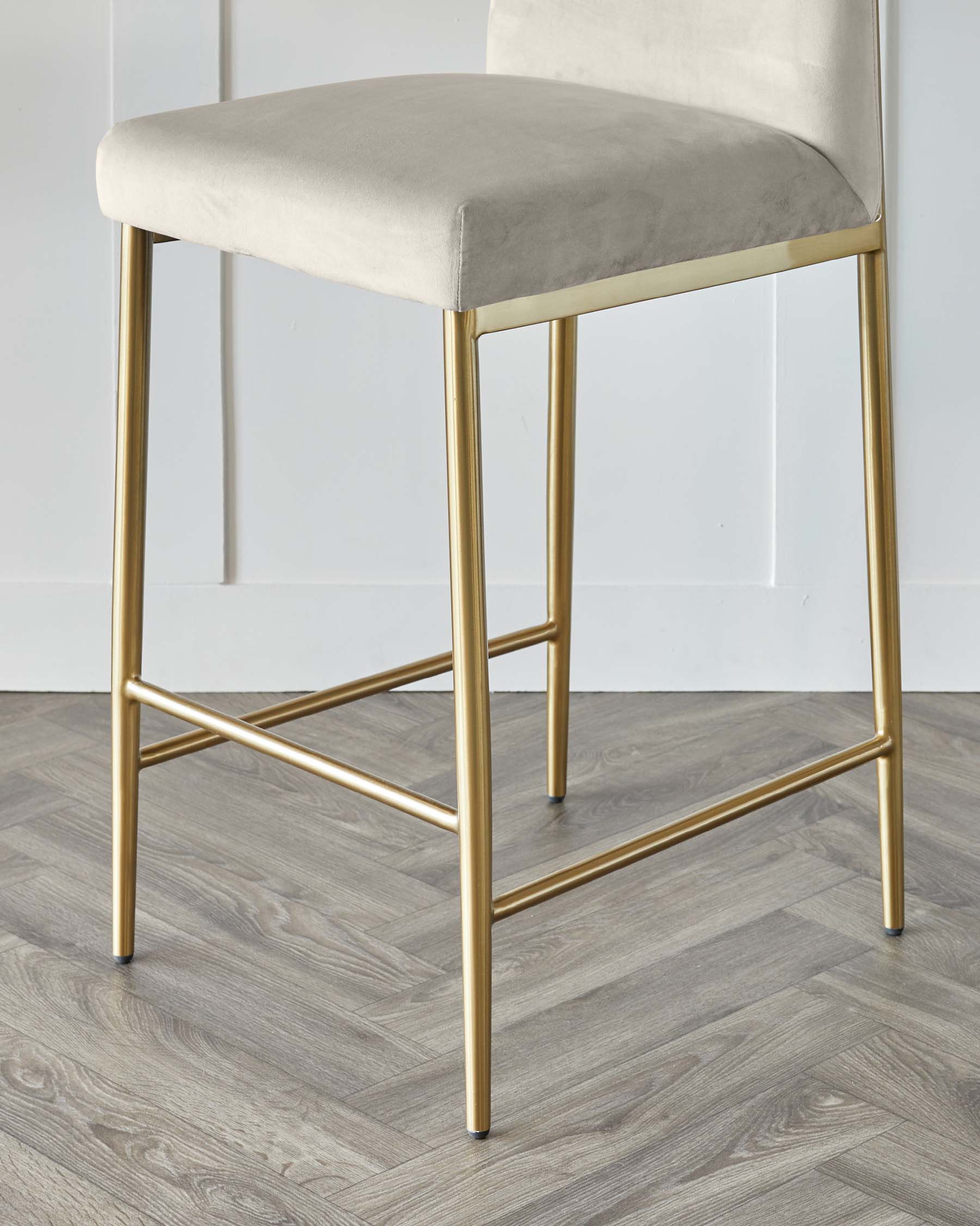 Modern bar stool with a minimalist design featuring a plush, light grey upholstered seat and a backrest, supported by a sleek, metallic gold finished frame with straight legs and footrests.