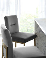 Elegant dining chairs with grey upholstery and a golden metal frame, accompanied by a white marble dining table.