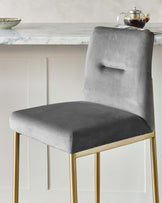 Elegant modern dining chair with a high backrest and plush grey velvet upholstery, featuring a rectangular cut-out detail. The chair stands on sleek, tapered golden metal legs, offering a luxurious and contemporary aesthetic.