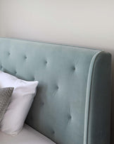 Elegant tufted upholstered headboard in a soft teal colour with a subtle wingback design.