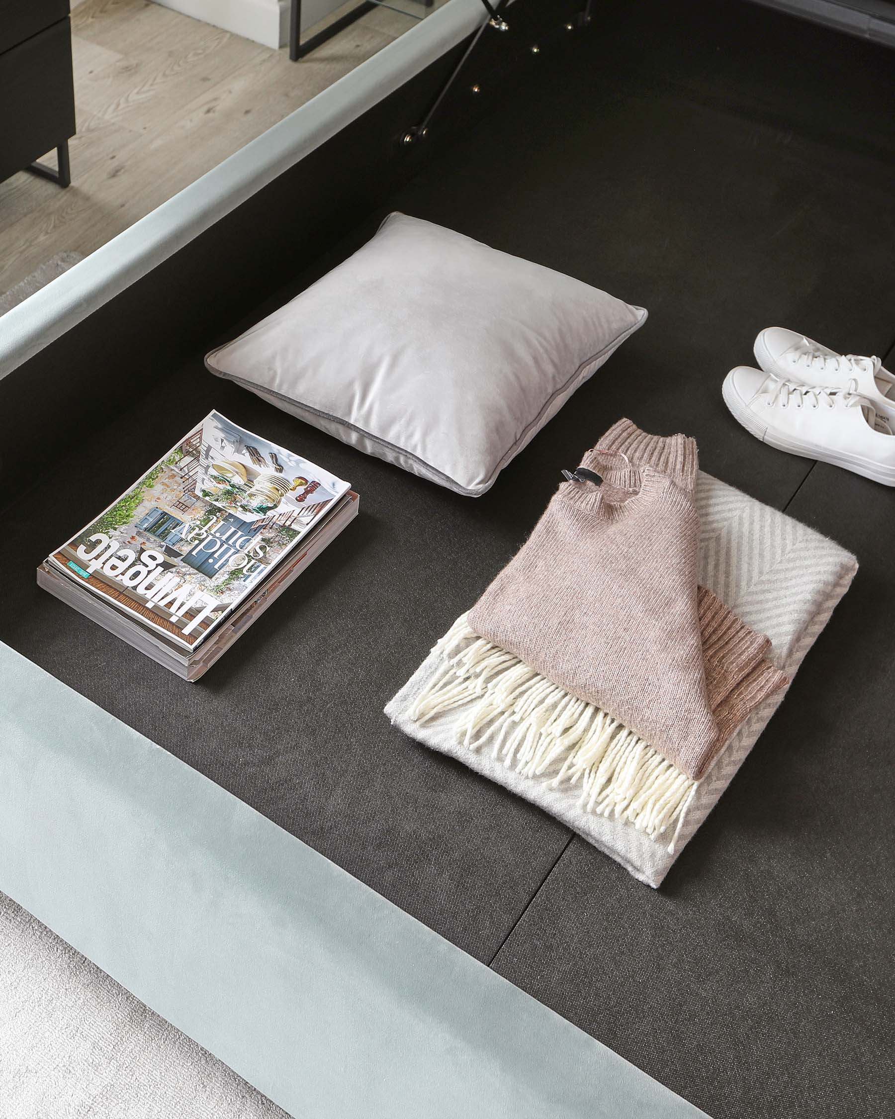 Modern minimalist low-profile platform bed frame in a room with a charcoal rug and light hardwood flooring.