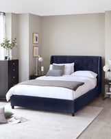 Elegant bedroom furniture set featuring a deep navy upholstered bed with a tufted headboard, flanked by two matching nightstands, and complemented by a sleek, tall dark grey dresser. Each piece showcases clean lines and a contemporary aesthetic.