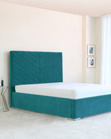 Elegant teal upholstered bed frame with a high, vertical channel-tufted headboard and a matching low-profile base situated on small, discrete feet in a modern bedroom setting.