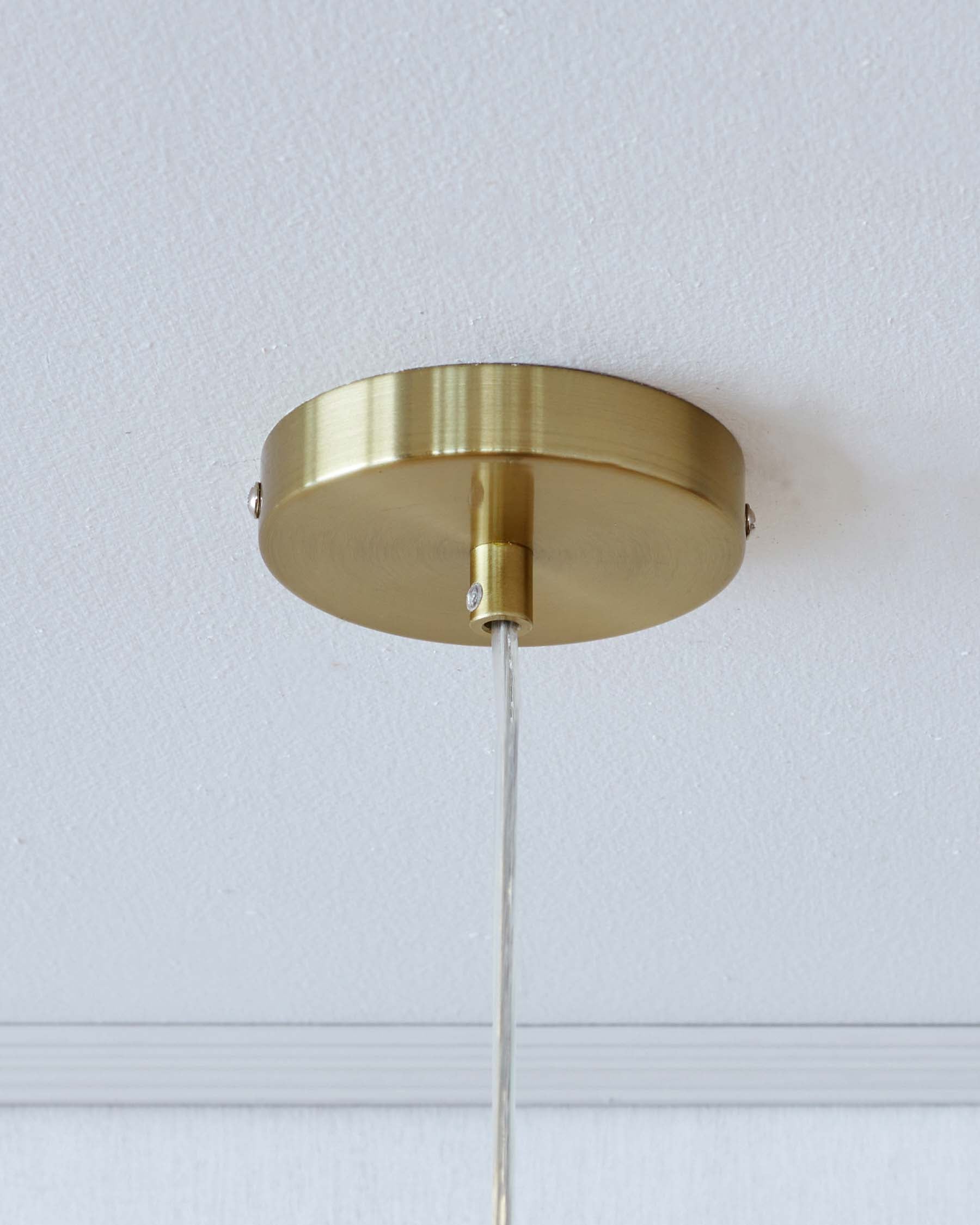 The image shows a brushed gold ceiling mount for a lighting fixture, with a visible textured surface. There is no furniture visible in this picture.