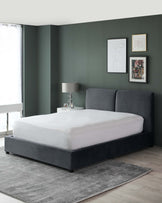 Elegant modern bedroom featuring a dark grey upholstered platform bed with a minimalist headboard, set on a light grey area rug over pale wooden flooring.