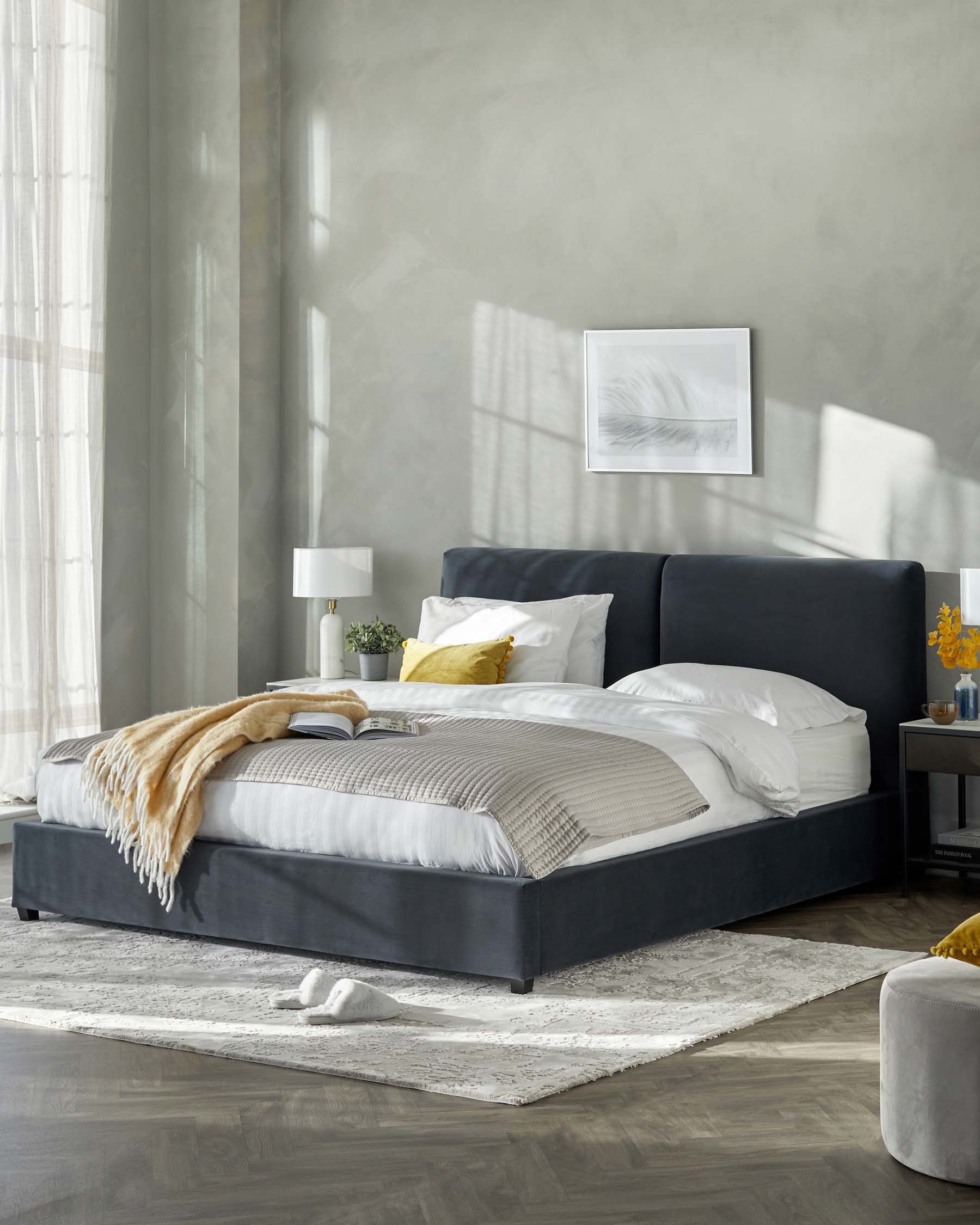 Elegant bedroom showcasing a king-sized bed with a dark upholstered headboard and platform frame, topped with white and grey striped bedding and accent pillows. A light beige throw blanket adds a cosy touch. Flanking the bed are two modern nightstands in a dark finish, each with a white lamp. The scene is grounded by a large, textured area rug in shades of white and grey.