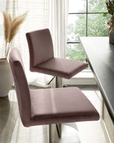 Modern mauve upholstered dining chair with a sleek profile and slender metal legs, positioned next to a dark-toned dining table with a reflective surface, in a bright room with sheer curtains.