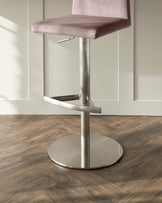 Modern adjustable swivel bar stool with a minimalist design, featuring a dusted pink upholstered seat and sleek brushed metal base with a footrest.