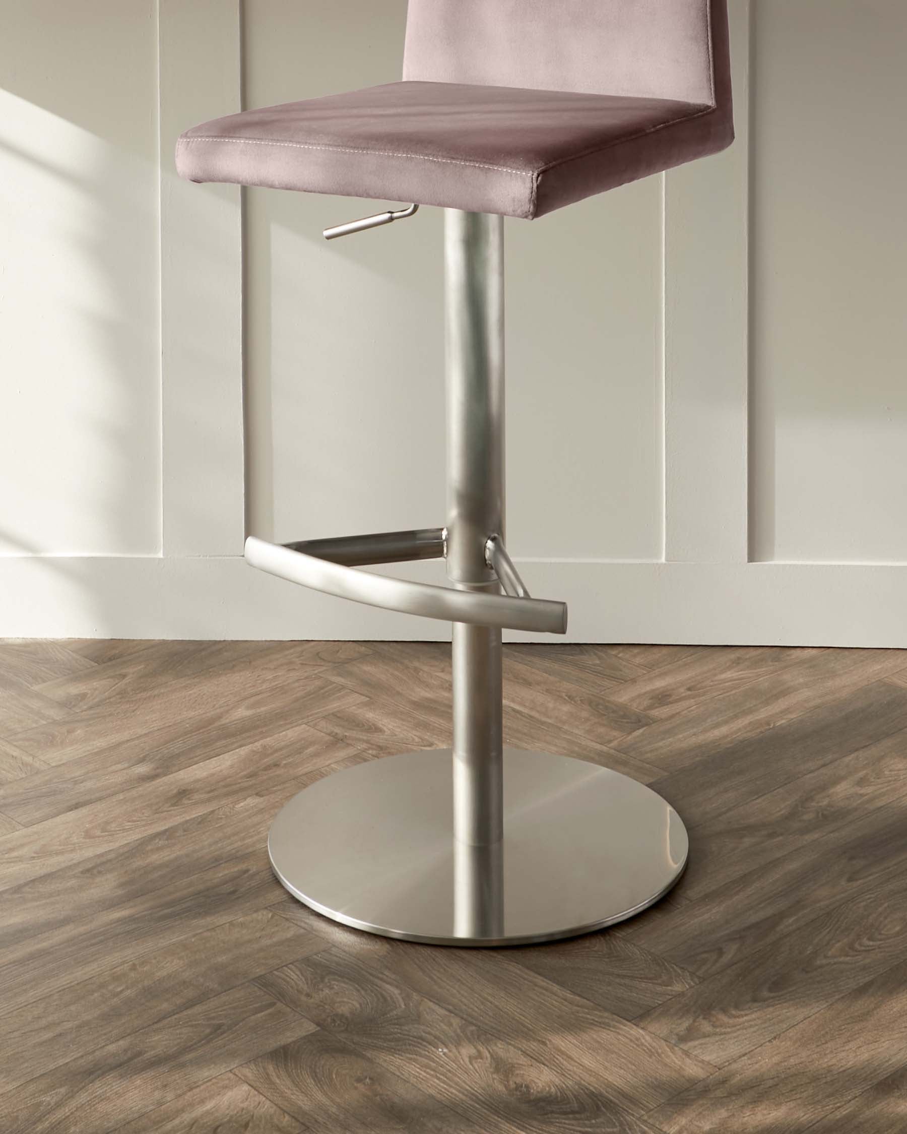 Modern adjustable swivel bar stool with a minimalist design, featuring a dusted pink upholstered seat and sleek brushed metal base with a footrest.