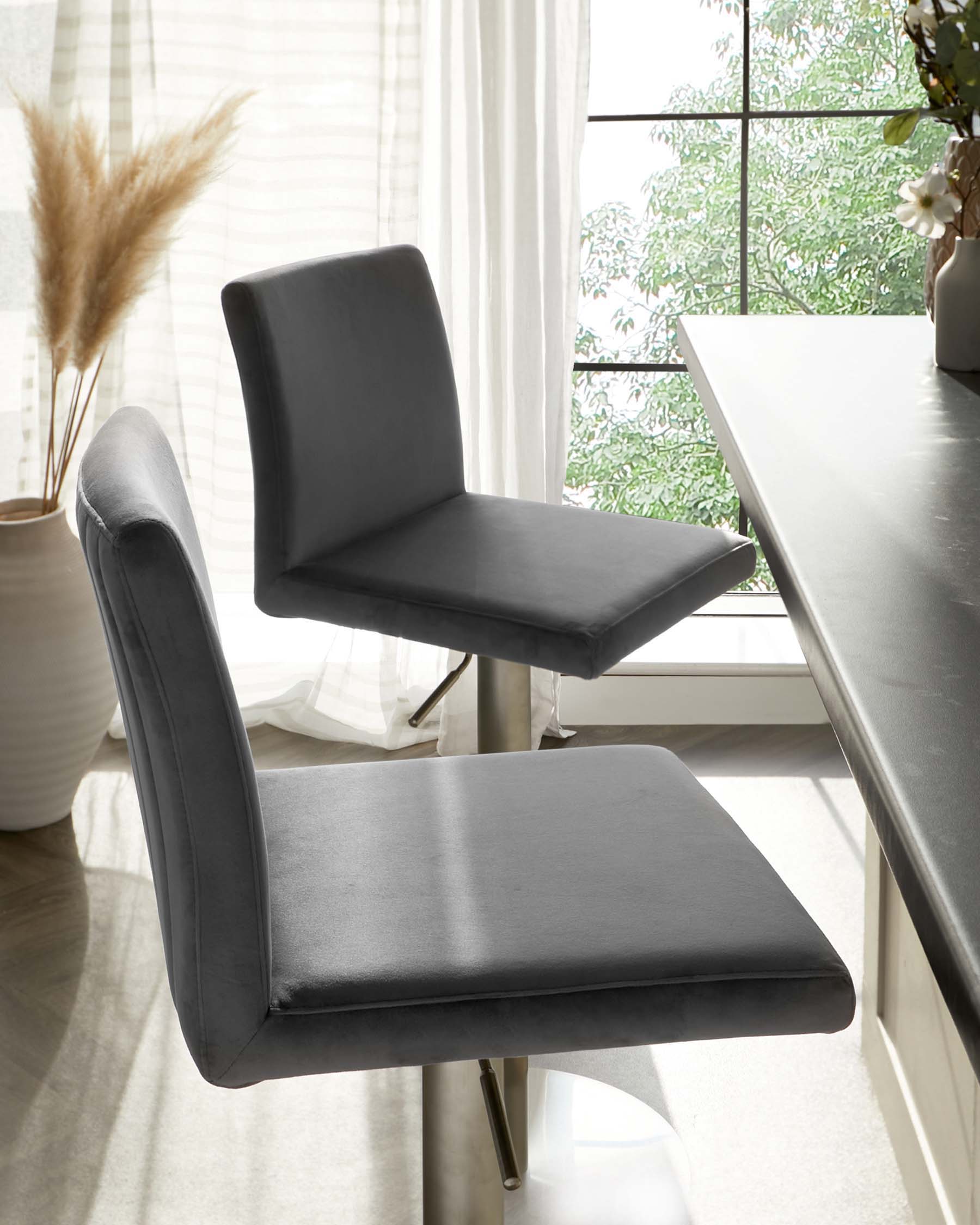 Modern minimalist dining chair with a sleek faux leather finish in a subtle grey tone. Features a straight backrest and a comfortable, flat seat mounted on a sturdy, metallic central pedestal base with a sleek silhouette. Ideal for contemporary dining spaces.