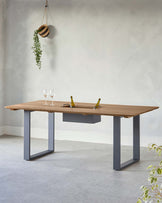 Modern wooden dining table with a sleek, gray metal base, featuring a central storage section and decorative wine bottles.