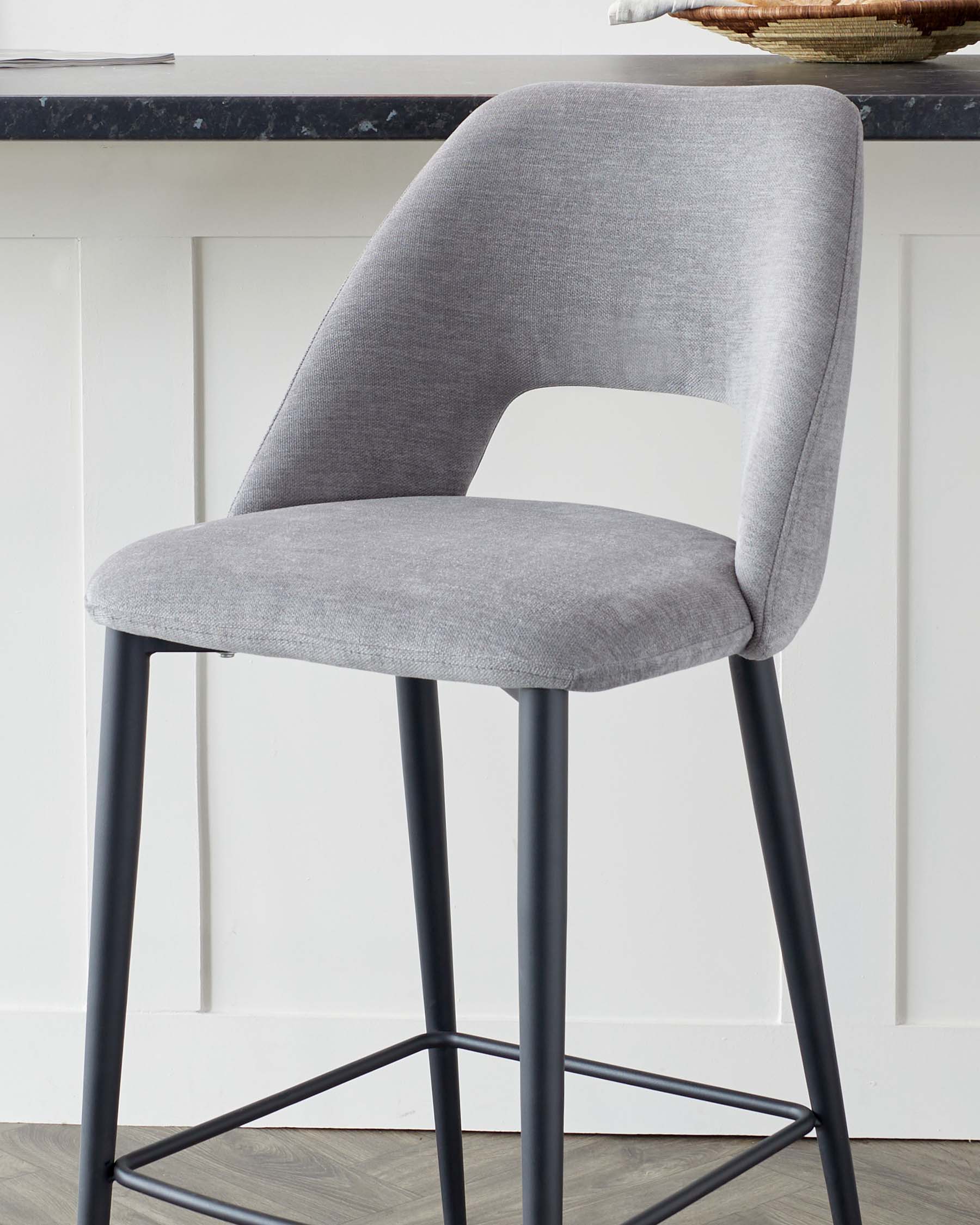 Modern grey upholstered dining chair with a curved backrest and matte black metal legs.