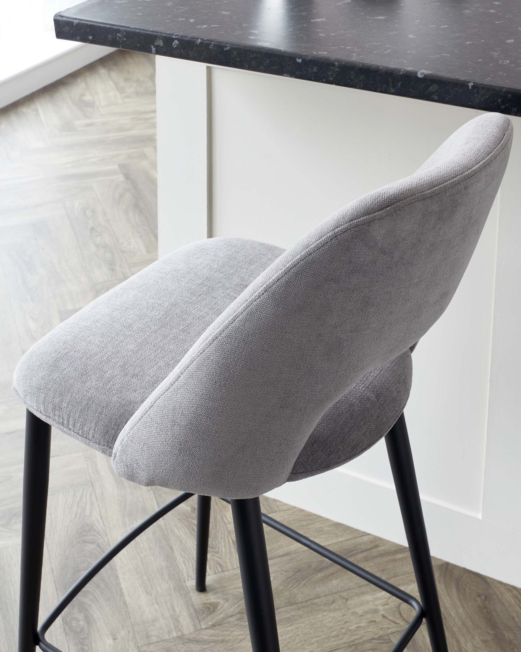 Modern light grey upholstered bar stool with a curved backrest and slim, black metal legs.