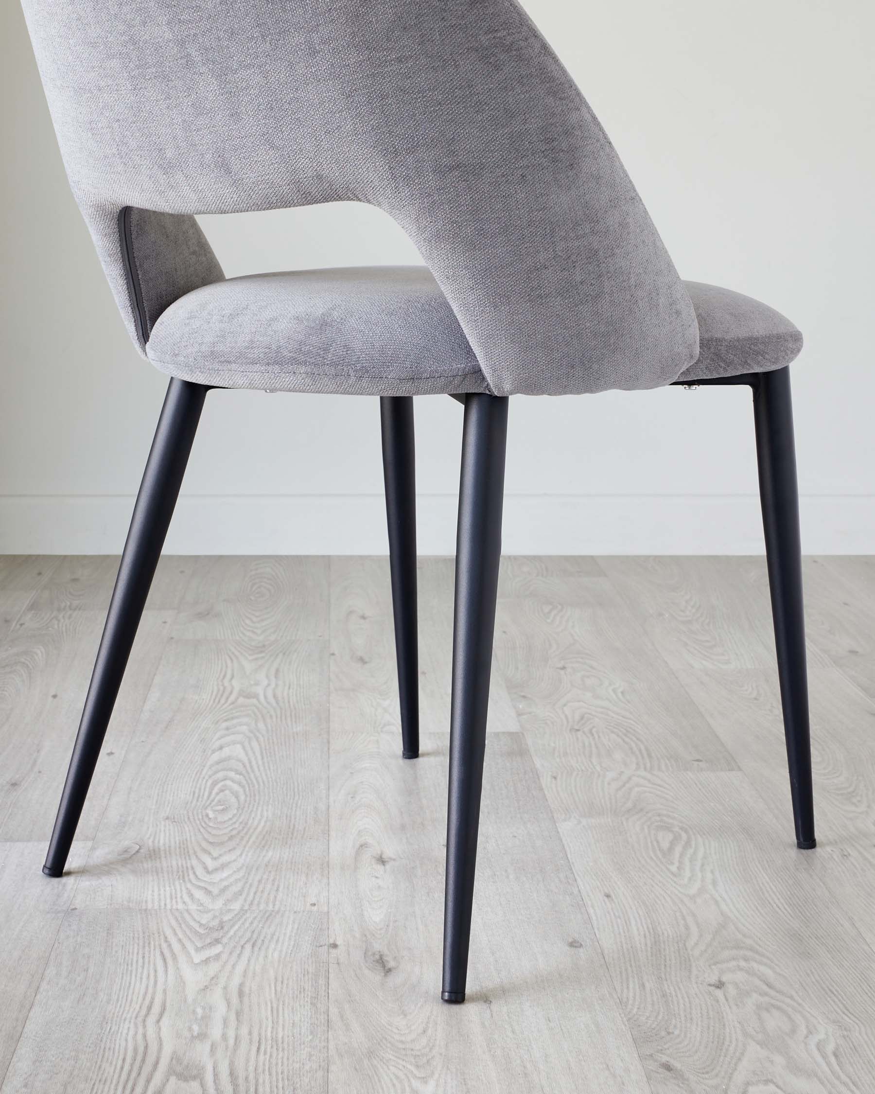 Modern dining chair with a sleek grey fabric upholstery and black metal legs.