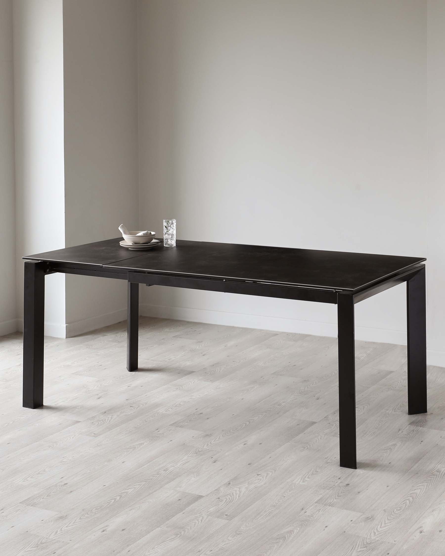 Modern minimalist black dining table with a rectangular top and four straight legs.