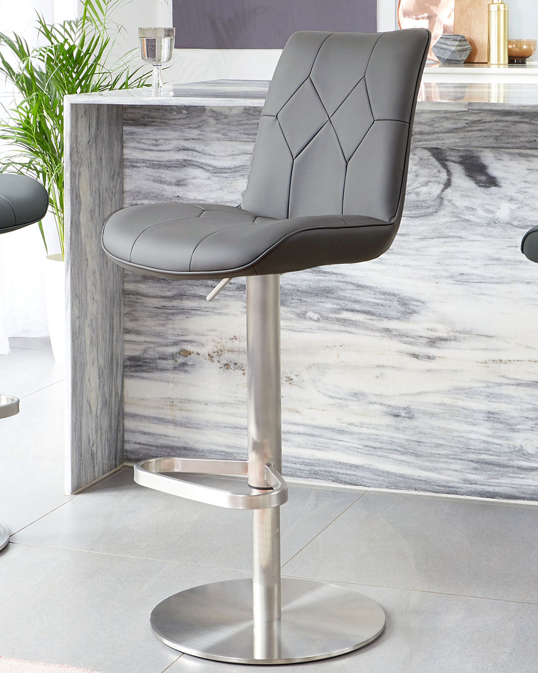 Modern grey bar stool with diamond tufting detail on backrest, a curved seat, and a chrome pedestal base with footrest.