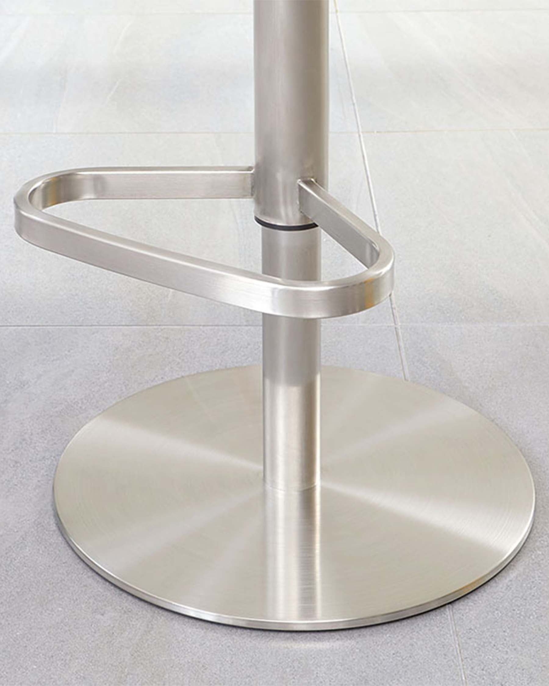 Polished stainless steel circular base of a bar stool with a centred supporting column and an attached footrest ring.