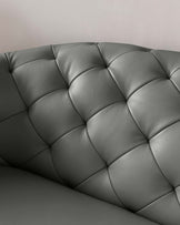 Close-up of a section of a charcoal grey leather tufted sofa with deep button accents, showcasing plush upholstery and a luxurious, elegant design.