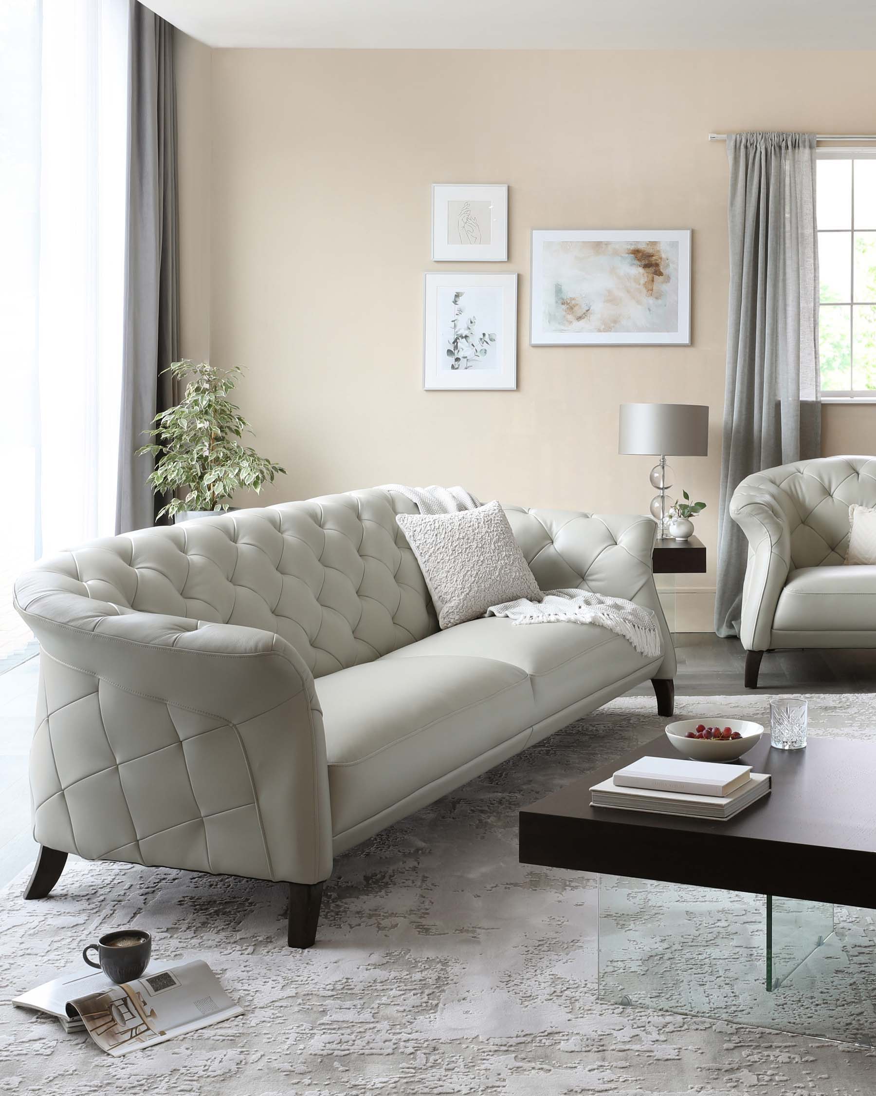 Elegant contemporary living room set featuring a tufted cream sofa and matching armchair with dark wooden legs, accompanied by a simple rectangular coffee table with a glass surface and dark wood finish.