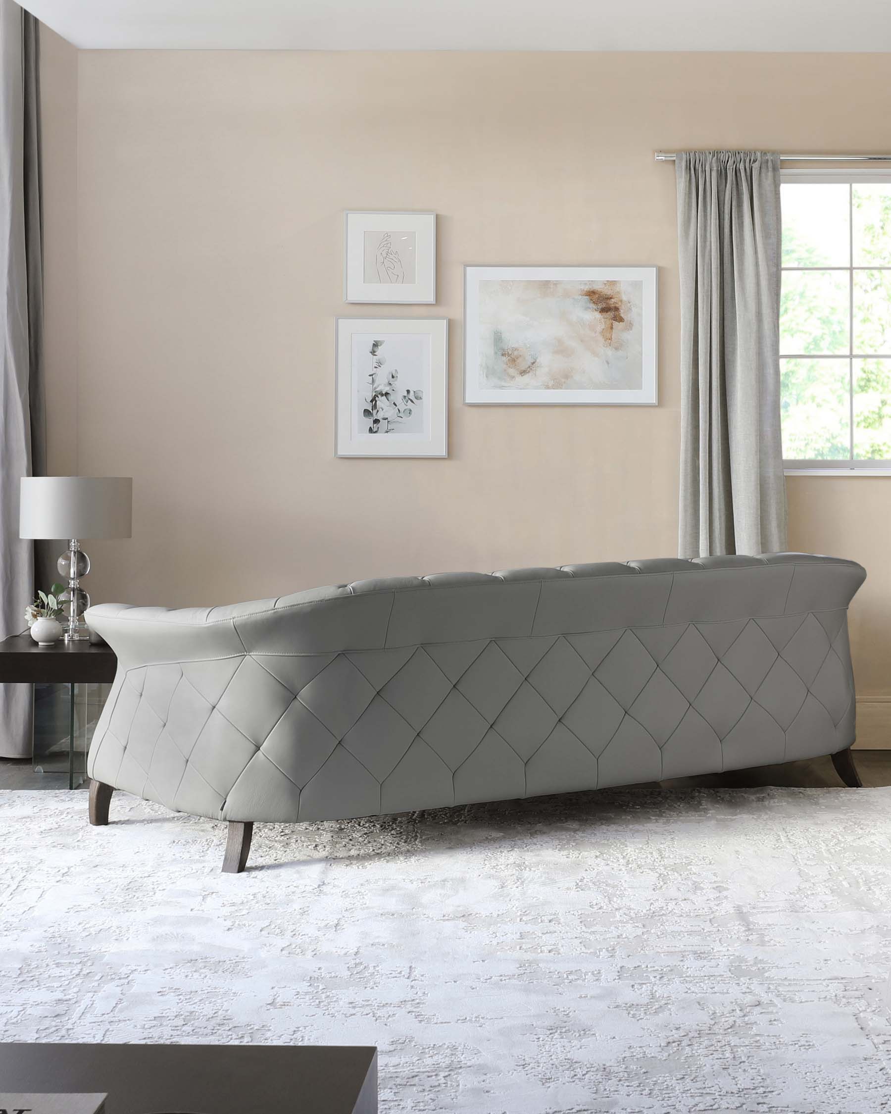 Elegant light grey tufted chaise lounge with a curvaceous form and geometric diamond stitching, set on tapered wooden legs.