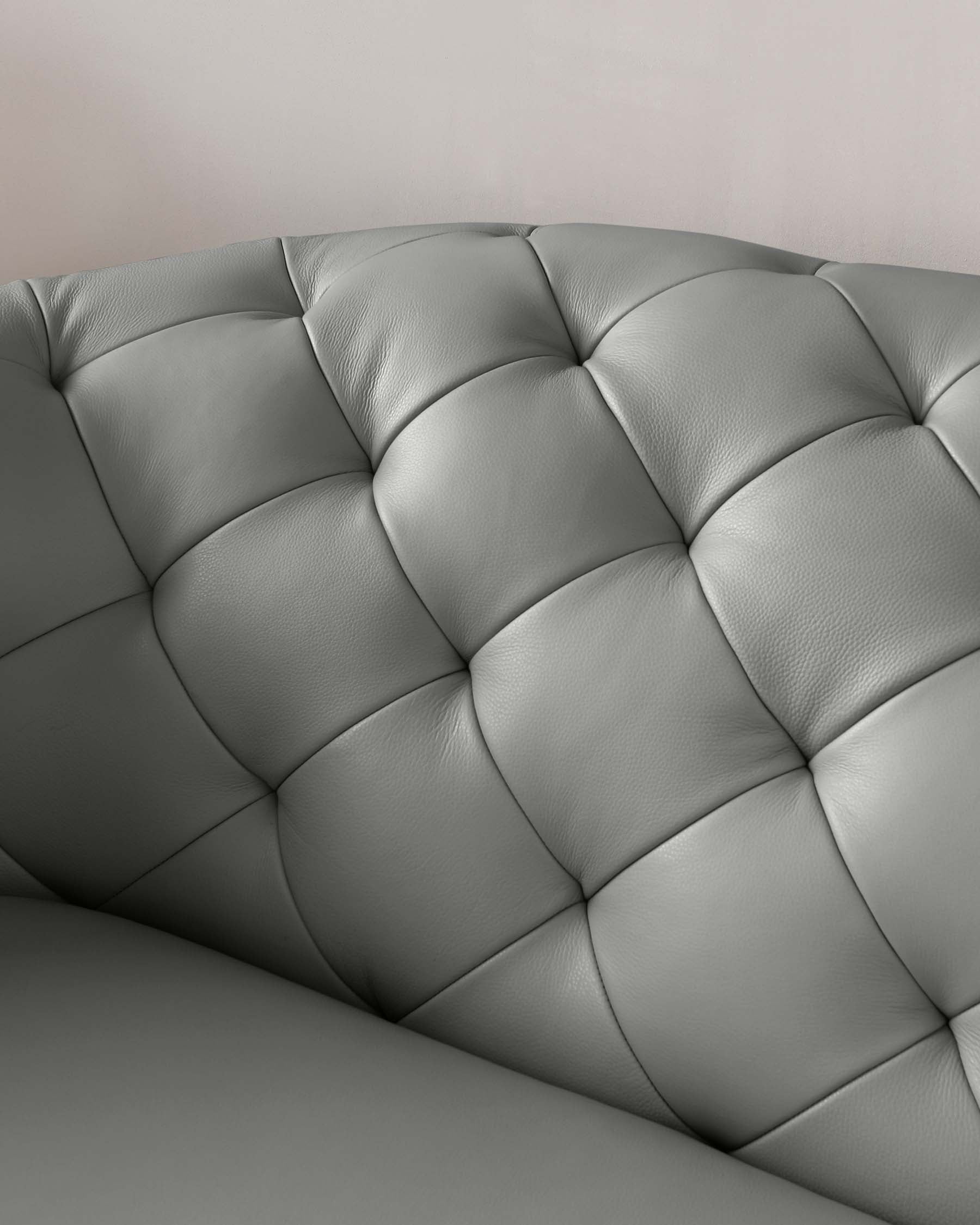 Close-up of a luxurious grey leather sofa with tufted upholstery.