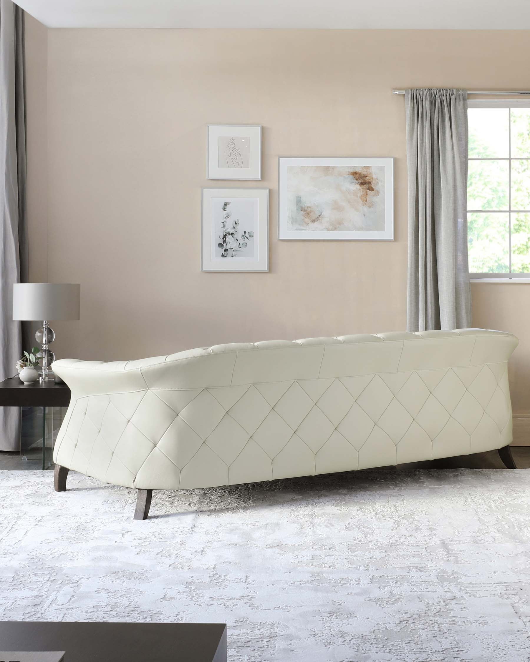 Elegant, contemporary cream-colored tufted sofa with geometric diamond stitching and dark wooden legs, set against a neutral-toned living room backdrop.