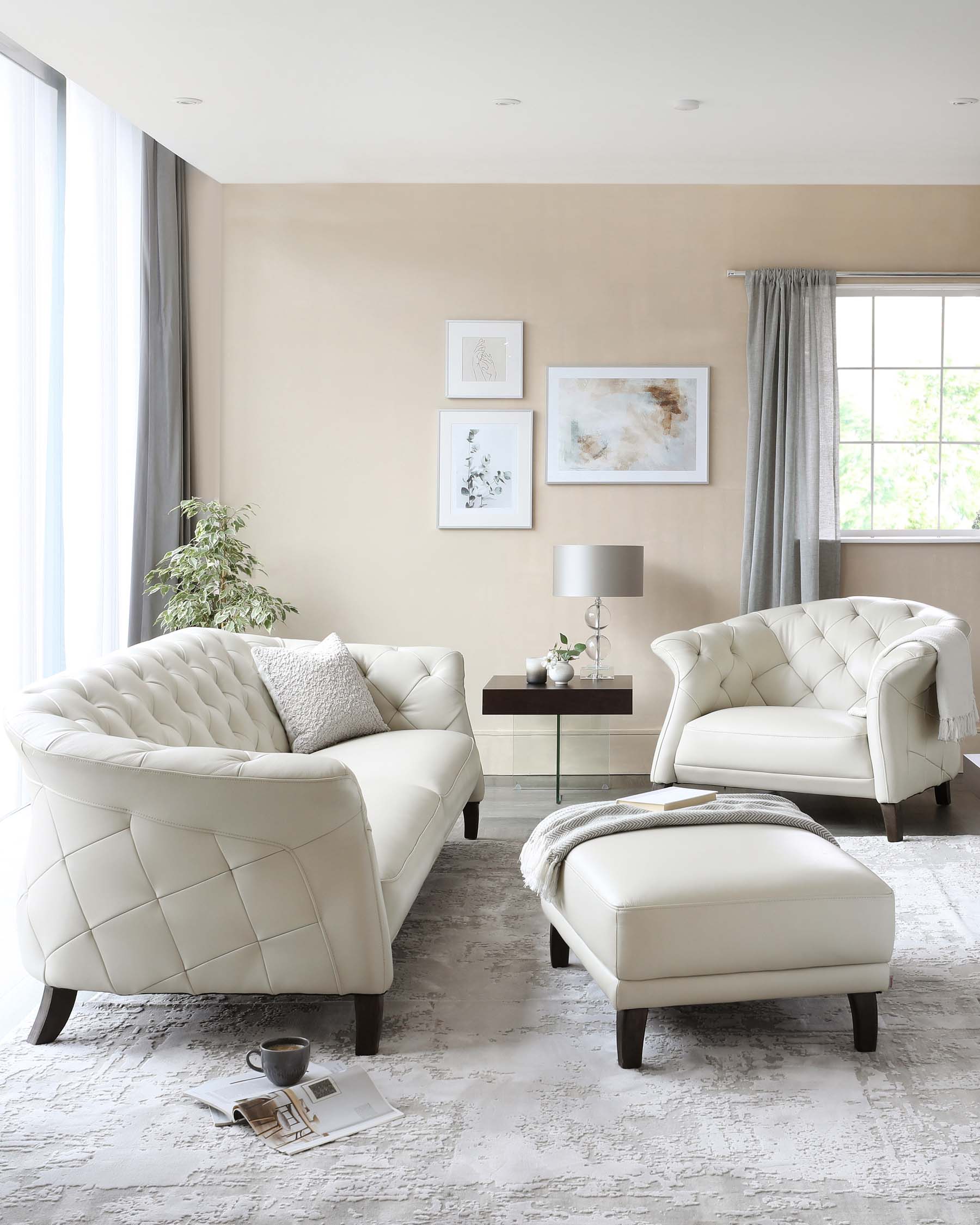 Elegant living room set featuring a white tufted leather sofa with a matching armchair and ottoman, all with dark wooden legs. A simple side table with a lamp and a modern coffee table with a throw blanket and book atop it complete the scene, set against a soft patterned area rug.