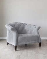 Elegant grey fabric loveseat with tufted back and armrests, featuring dark wooden legs, placed on a light hardwood floor against a plain white wall.