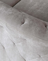 Close-up of a modern light grey fabric sofa showing detailed texture and geometric pattern stitching on the upholstery.