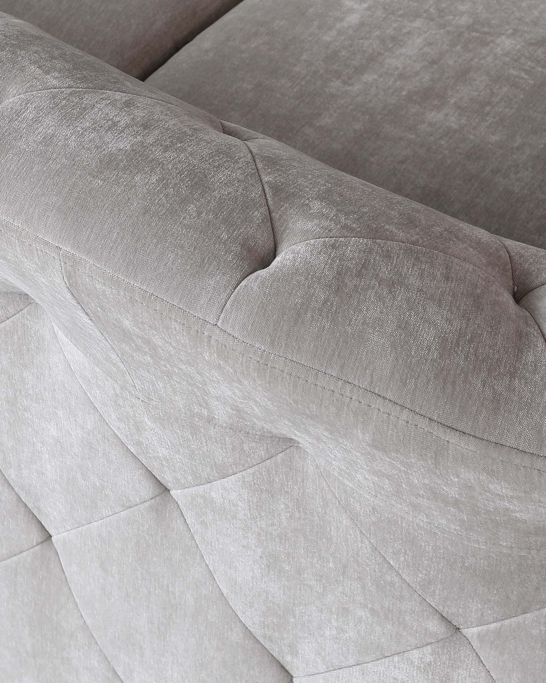 Close-up view of a contemporary sofa with textured grey upholstery, showcasing geometric stitching details and plush cushioning.