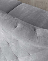 Close-up view of a modern light grey fabric sofa with a smooth, plush finish and subtle quilting detail on the armrest.