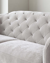 Close-up of a contemporary sofa featuring a tufted, plush backrest in a soft, light grey fabric with a subtle sheen, conveying a luxurious and comfortable look.