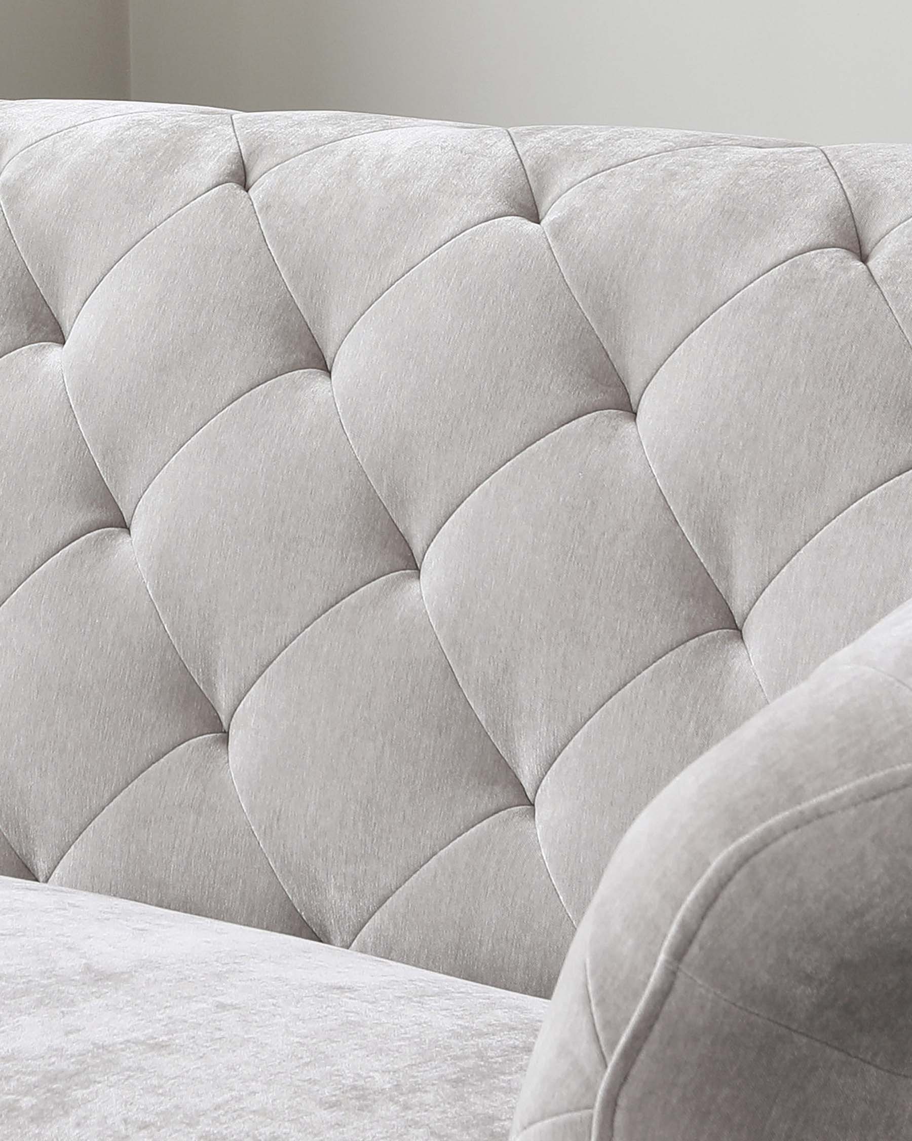 Close-up of a light grey tufted fabric sofa showcasing its textured upholstery and plush cushioning in a scalloped pattern.